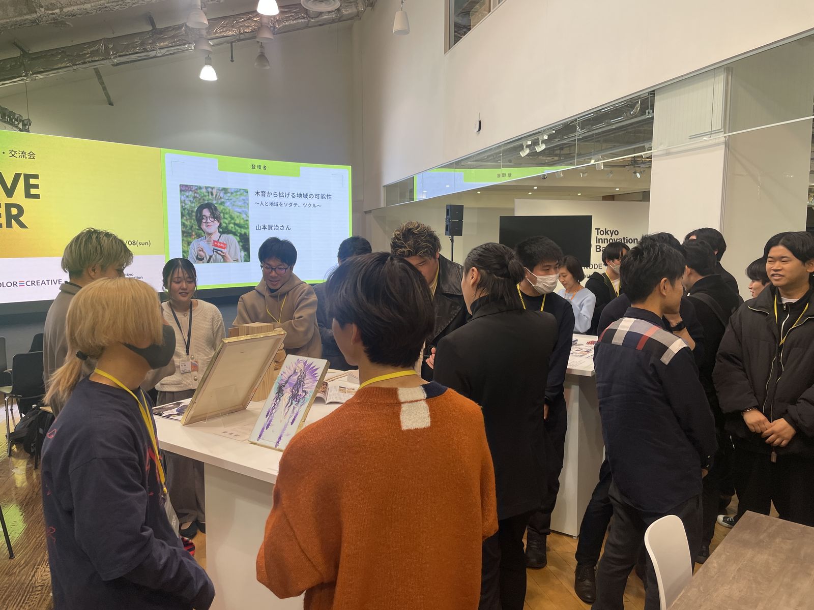 過去開催の交流会：展示台を囲んで話す参加者